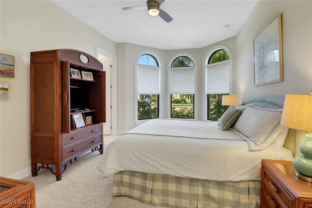 bedroom with a ceiling fan, multiple windows, light carpet, and baseboards