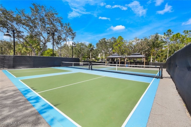 view of property's community featuring a tennis court, a gazebo, and fence