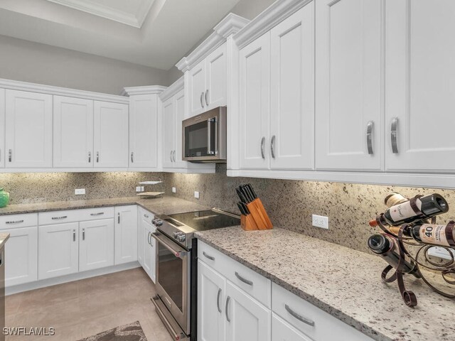 kitchen with light stone counters, white cabinets, backsplash, and appliances with stainless steel finishes