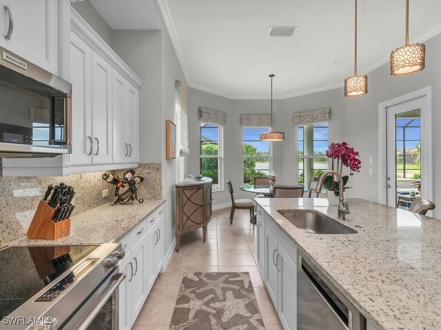 kitchen with stainless steel appliances, light stone countertops, pendant lighting, white cabinets, and sink