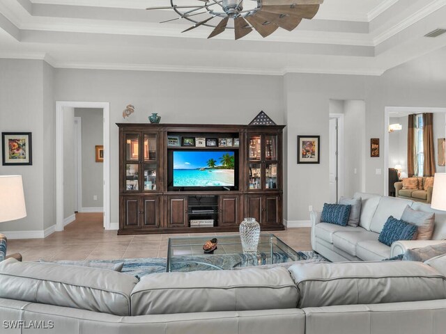 living room with ceiling fan, light tile patterned floors, crown molding, and a tray ceiling