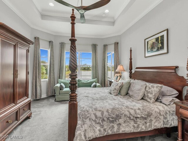 carpeted bedroom with ceiling fan and a raised ceiling