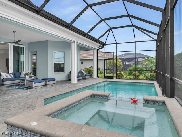 view of pool featuring glass enclosure, ceiling fan, an outdoor living space, an in ground hot tub, and a patio