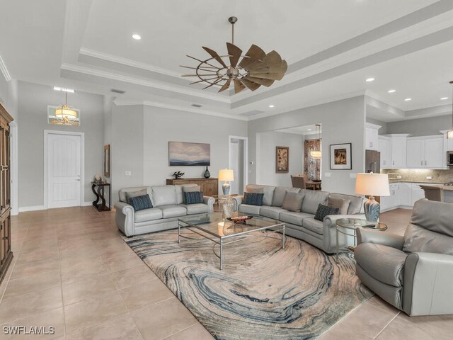 tiled living room featuring ceiling fan, ornamental molding, and a raised ceiling