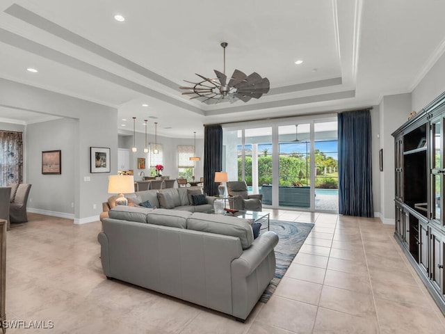 living room featuring ceiling fan, ornamental molding, a raised ceiling, and light tile patterned flooring