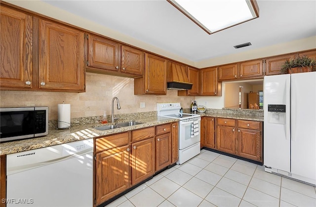 kitchen with light tile patterned flooring, sink, light stone counters, and white appliances