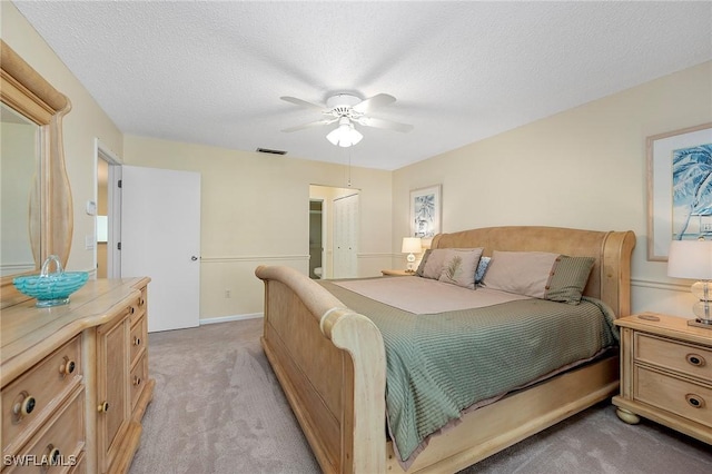 bedroom featuring ceiling fan, light carpet, and a textured ceiling