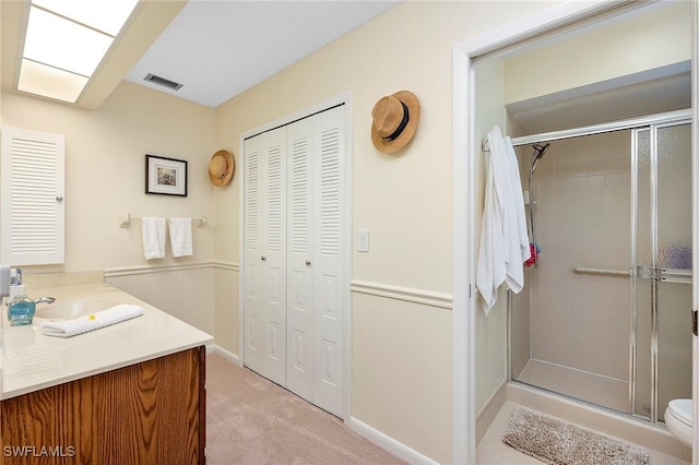 bathroom with a shower with shower door, toilet, and vanity