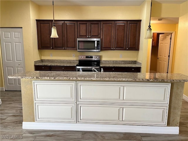 kitchen with pendant lighting, dark brown cabinets, a kitchen island, and appliances with stainless steel finishes