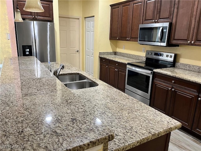 kitchen with light stone counters, sink, stainless steel appliances, and dark brown cabinets