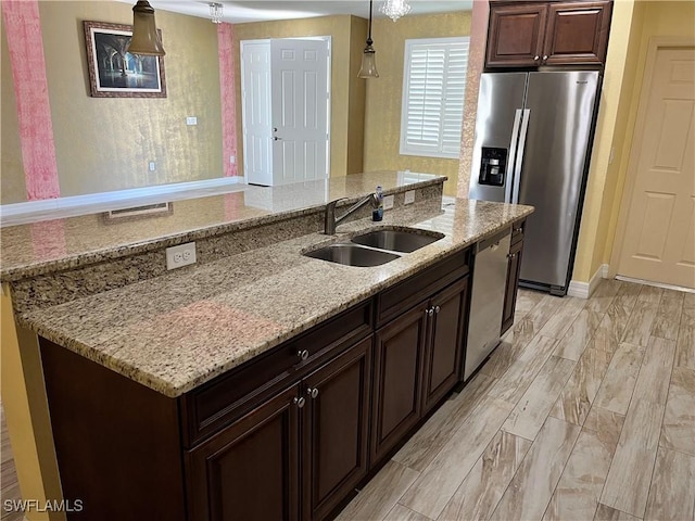 kitchen featuring appliances with stainless steel finishes, dark brown cabinetry, decorative light fixtures, and sink