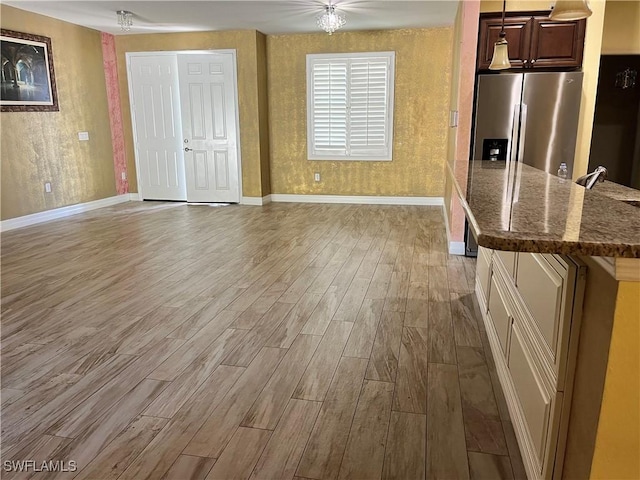 kitchen featuring sink, hardwood / wood-style floors, stainless steel refrigerator with ice dispenser, and an inviting chandelier