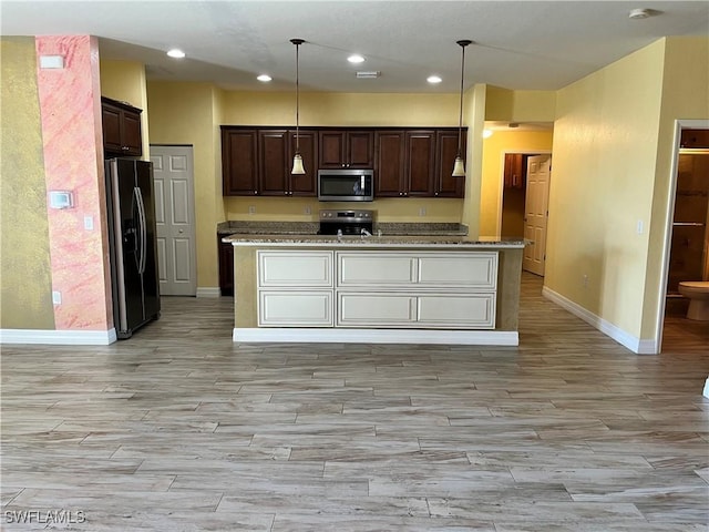 kitchen featuring decorative light fixtures, dark brown cabinetry, stainless steel appliances, and a center island with sink