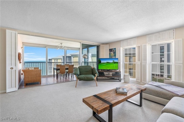 carpeted living room with a healthy amount of sunlight, ceiling fan, and a textured ceiling