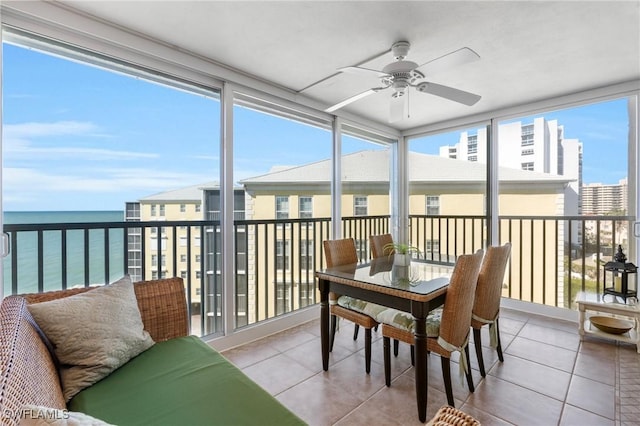 sunroom with ceiling fan and a water view