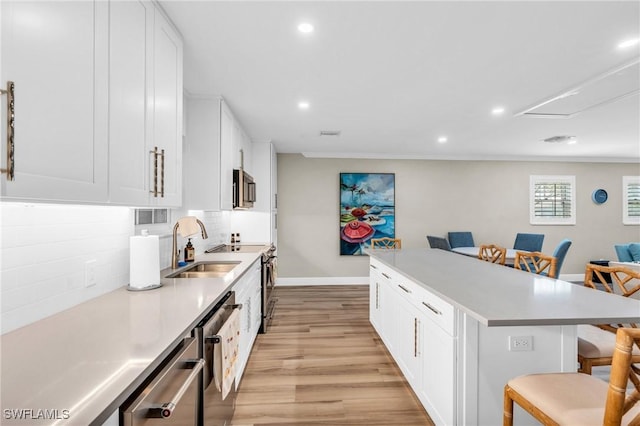 kitchen featuring tasteful backsplash, a kitchen bar, a kitchen island, white cabinets, and appliances with stainless steel finishes