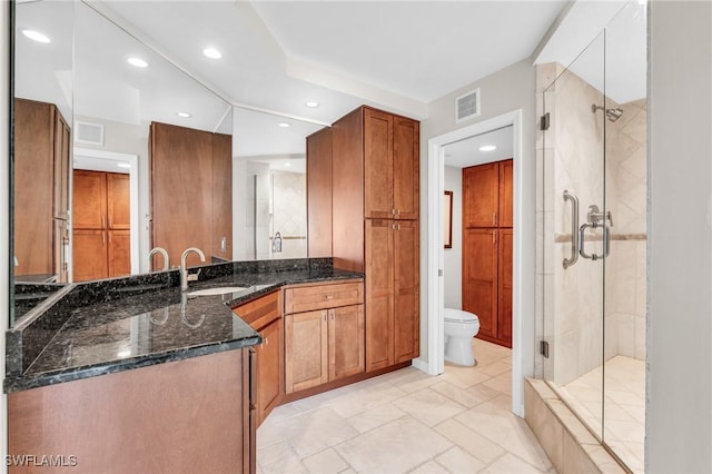 bathroom featuring vanity, a shower with shower door, and toilet