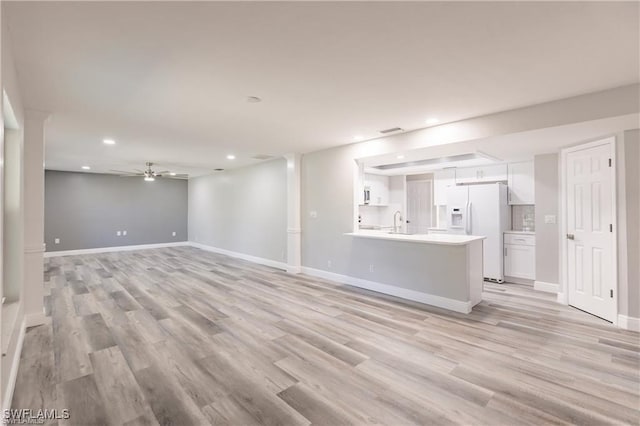 unfurnished living room with ceiling fan, sink, and light hardwood / wood-style flooring