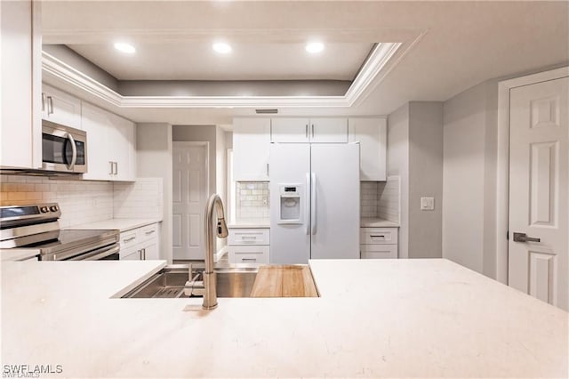 kitchen with backsplash, sink, white cabinets, and appliances with stainless steel finishes