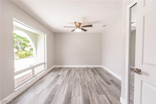 empty room featuring ceiling fan, plenty of natural light, and light wood-type flooring