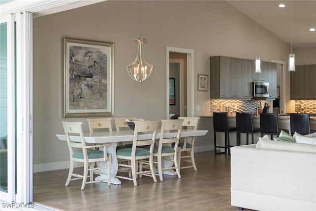 dining space featuring high vaulted ceiling, dark hardwood / wood-style floors, and a notable chandelier