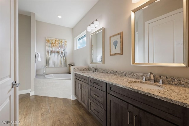 bathroom featuring hardwood / wood-style floors, vanity, and tiled tub