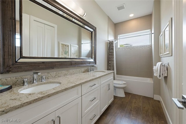 full bathroom with hardwood / wood-style floors, vanity, shower / tub combo, and toilet