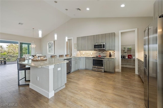 kitchen with hanging light fixtures, stainless steel appliances, tasteful backsplash, kitchen peninsula, and a breakfast bar