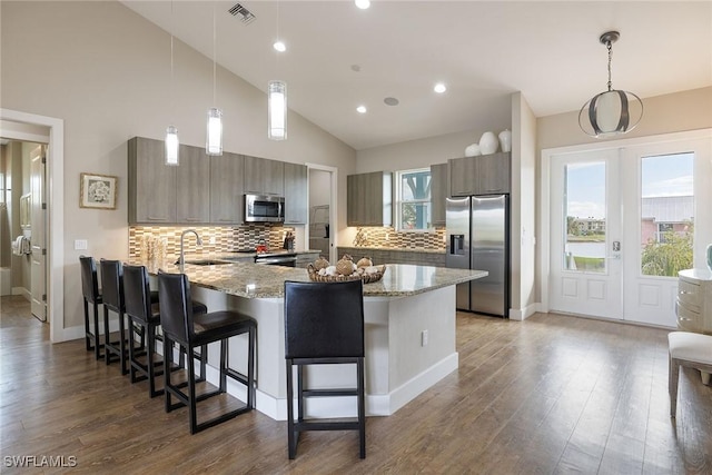 kitchen featuring kitchen peninsula, pendant lighting, stainless steel appliances, and sink