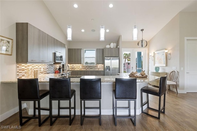 kitchen with pendant lighting, decorative backsplash, stainless steel appliances, and vaulted ceiling