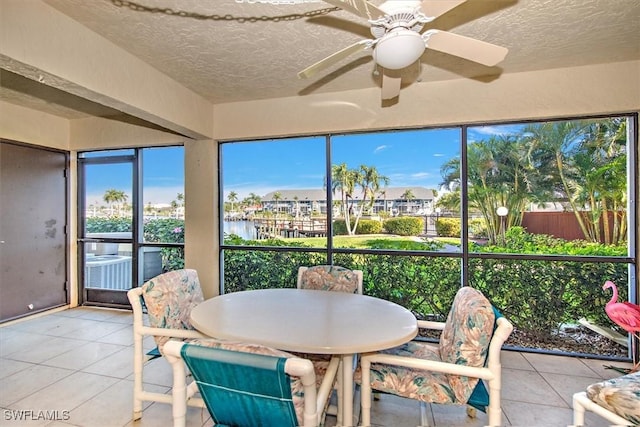 sunroom with ceiling fan and a water view