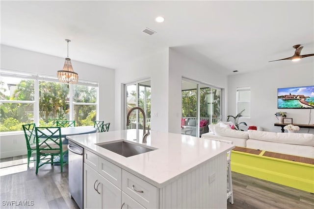 kitchen featuring sink, white cabinets, ceiling fan with notable chandelier, hanging light fixtures, and a kitchen island with sink