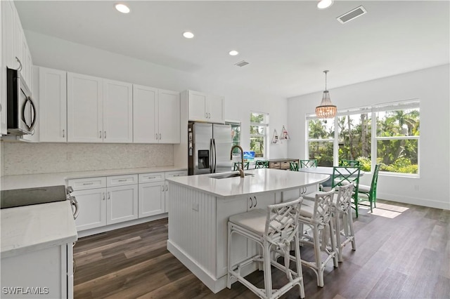 kitchen with sink, stainless steel appliances, white cabinetry, and decorative light fixtures