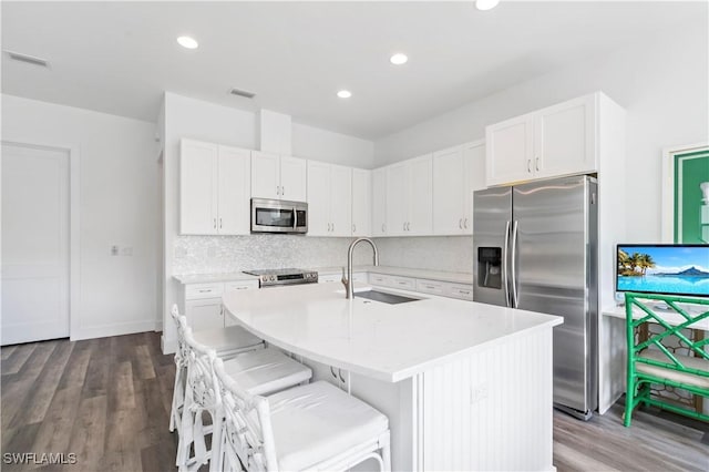 kitchen with sink, stainless steel appliances, white cabinetry, and a kitchen island with sink