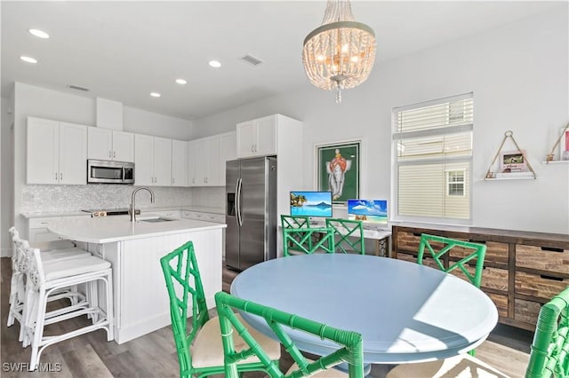 kitchen featuring stainless steel appliances, a notable chandelier, pendant lighting, decorative backsplash, and white cabinetry