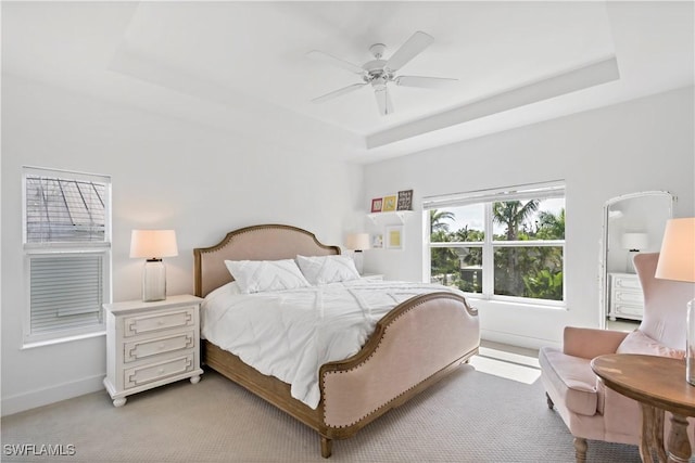 bedroom with ceiling fan, light carpet, and a raised ceiling