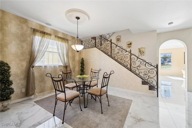 dining space featuring marble finish floor, baseboards, stairs, and arched walkways