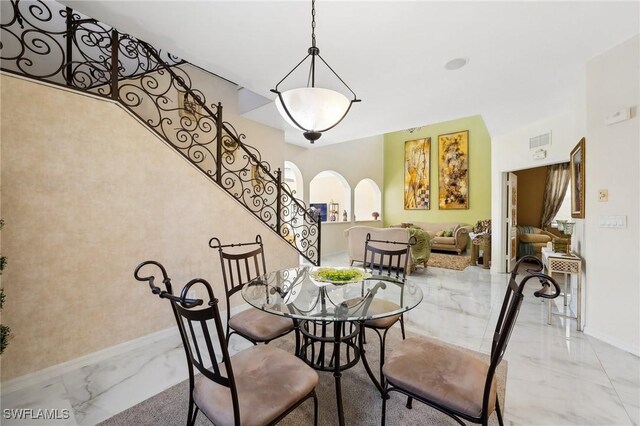 dining area featuring baseboards, arched walkways, visible vents, stairway, and marble finish floor