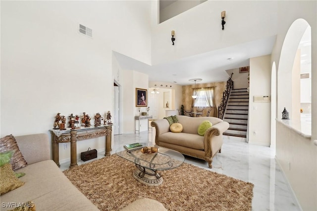 living area featuring arched walkways, visible vents, baseboards, marble finish floor, and stairway