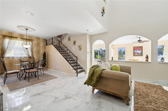 living area with stairs, marble finish floor, baseboards, and a healthy amount of sunlight