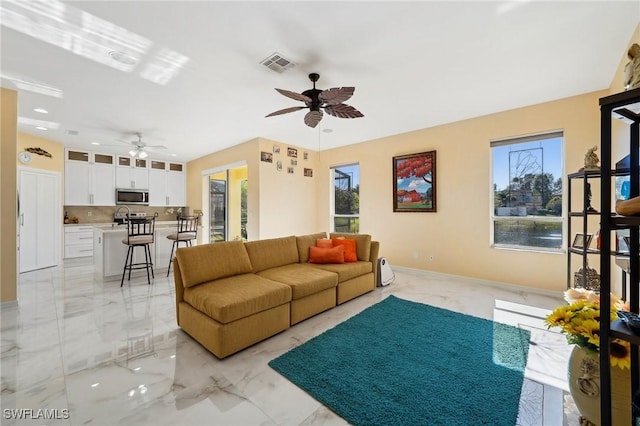 living room with baseboards, marble finish floor, visible vents, and a ceiling fan