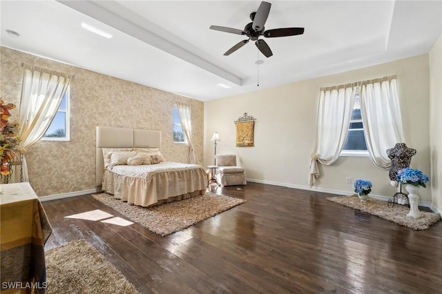 bedroom with dark wood-style floors, a raised ceiling, multiple windows, and baseboards