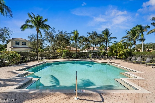 community pool with a patio area and fence