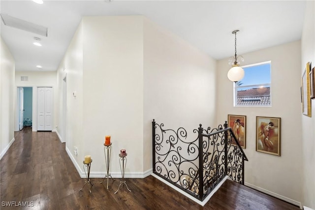 hall featuring dark wood-style floors, visible vents, an upstairs landing, and baseboards