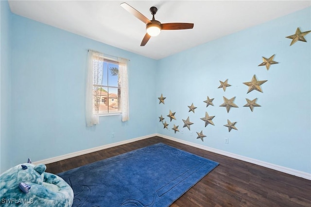 interior space featuring dark wood-type flooring, ceiling fan, and baseboards