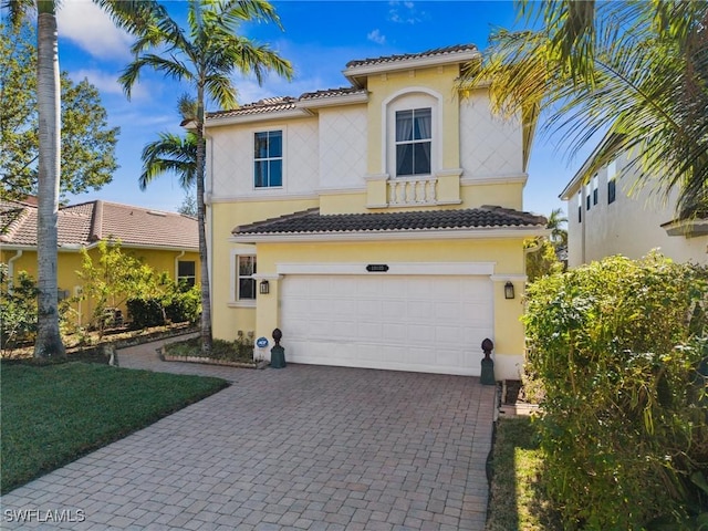 mediterranean / spanish house featuring a tiled roof, decorative driveway, an attached garage, and stucco siding