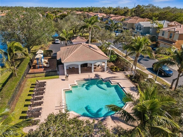 community pool featuring a residential view, fence, and a patio