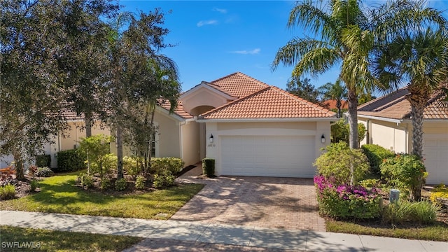 mediterranean / spanish-style home with a tiled roof, decorative driveway, an attached garage, and stucco siding