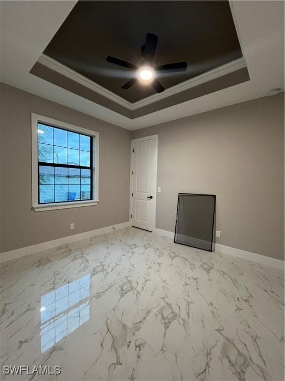 spare room featuring baseboards, a tray ceiling, ceiling fan, and crown molding