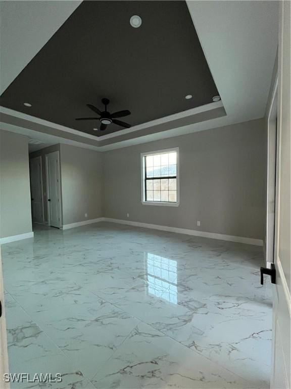 empty room with a raised ceiling and ceiling fan